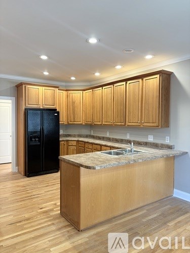 A kitchen with wooden cabinets and a black fridge.