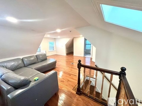 A living room with a grey couch and a skylight.