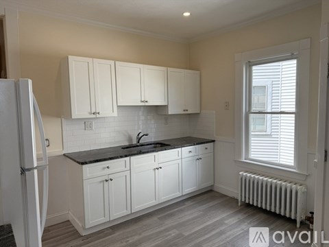 A kitchen with white cabinets and a black countertop.