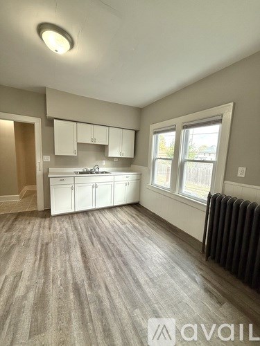 A room with a window, a radiator, and a kitchenette.