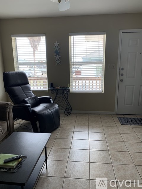 A living room with a black leather chair and a black coffee table.