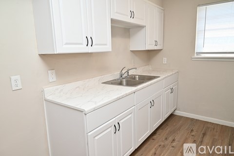 A kitchen with white cabinets and a marble countertop.