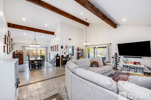 A living room with a grey couch and a wooden ceiling.