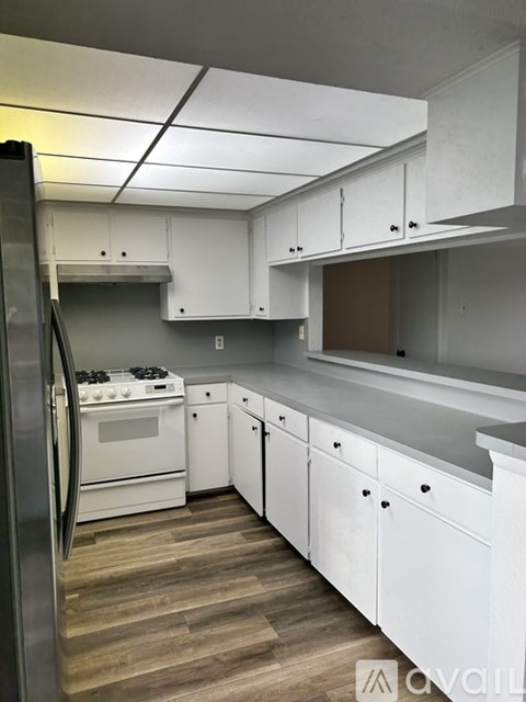 A kitchen with white cabinets and a stainless steel refrigerator.