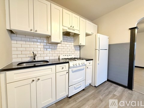A kitchen with white cabinets and black countertops.