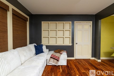 A living room with a white couch and a wooden floor.