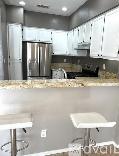 A kitchen with white cabinets and a marble countertop.