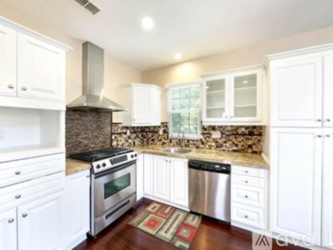 A kitchen with white cabinets and a stone backsplash.
