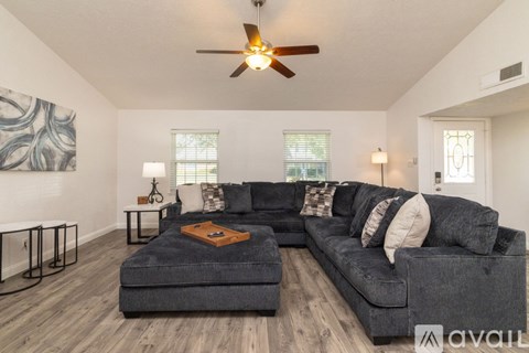 A living room with a grey couch and a ceiling fan.