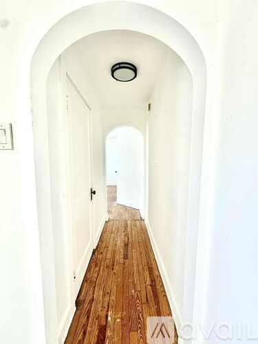 A long hallway with a wooden floor and white walls.