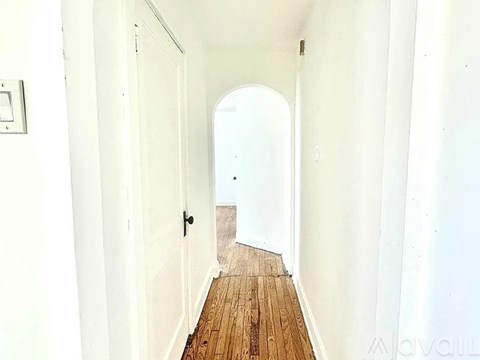 A long hallway with a wooden floor and white walls.