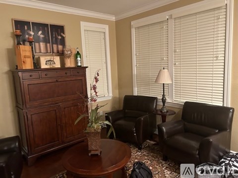 A living room with a brown leather chair, a wooden cabinet, and a table with a plant on it.