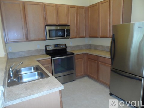 A kitchen with wooden cabinets and a stainless steel refrigerator.