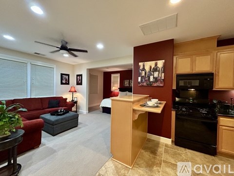 A living room with a red couch and a fan on the ceiling.