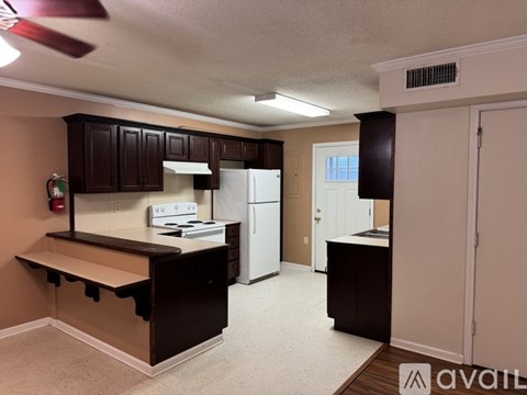 A kitchen with brown cabinets and a white refrigerator.