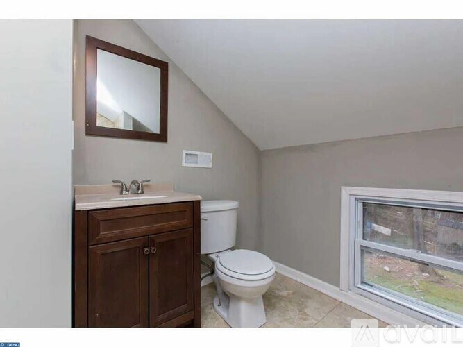 A bathroom with a toilet, sink, and a window.