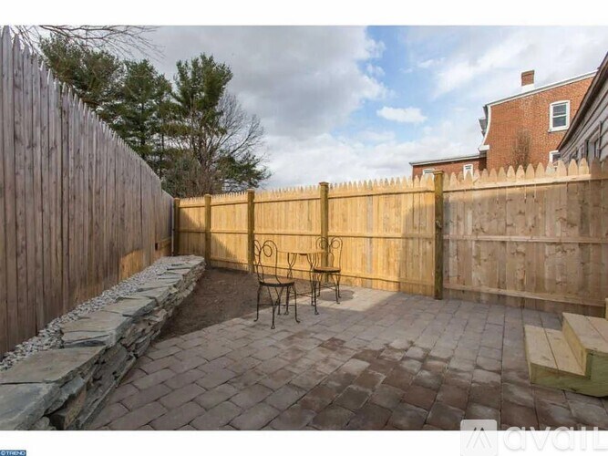 A backyard with a wooden fence and a stone bench.
