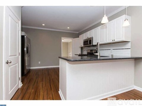A kitchen with white cabinets and a black countertop.