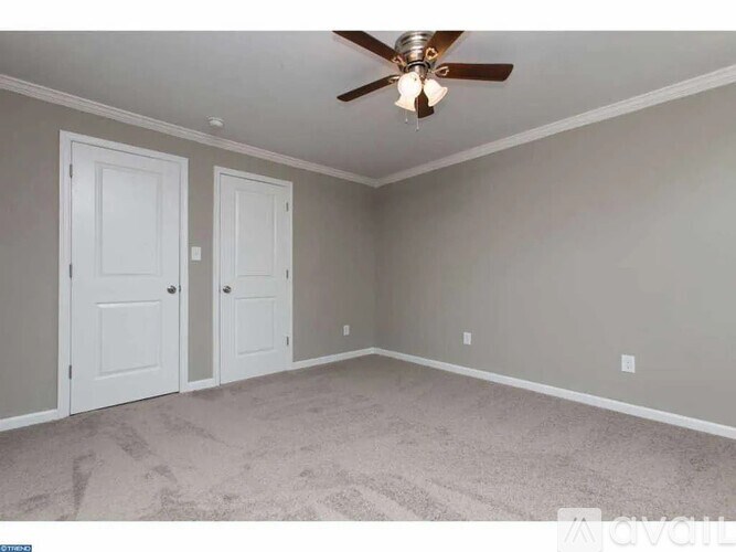 A room with a ceiling fan and two doors.