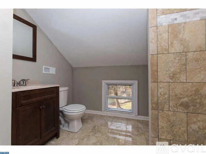 A bathroom with a toilet, sink, and a window.