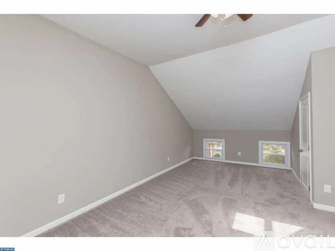 A spacious room with a ceiling fan and a window showing a view of a garden.