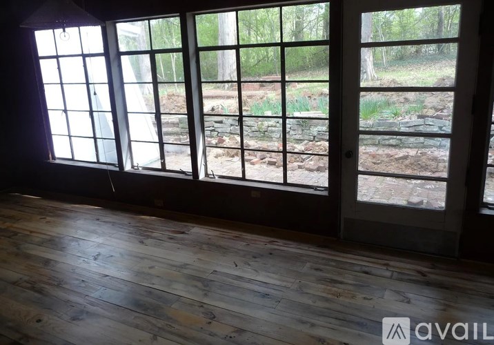 A room with wooden floors and large windows overlooking a garden.