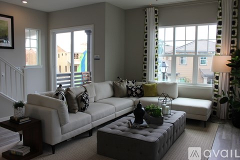 A living room with a white couch and a grey ottoman.