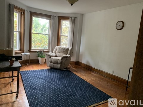 A living room with a white chair and a blue rug.