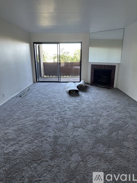 A living room with a grey carpet and a fireplace.