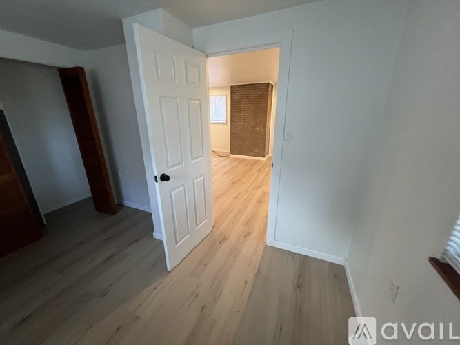 A white door is open to a room with wooden flooring.