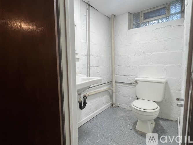 A white toilet in a small bathroom with a window.
