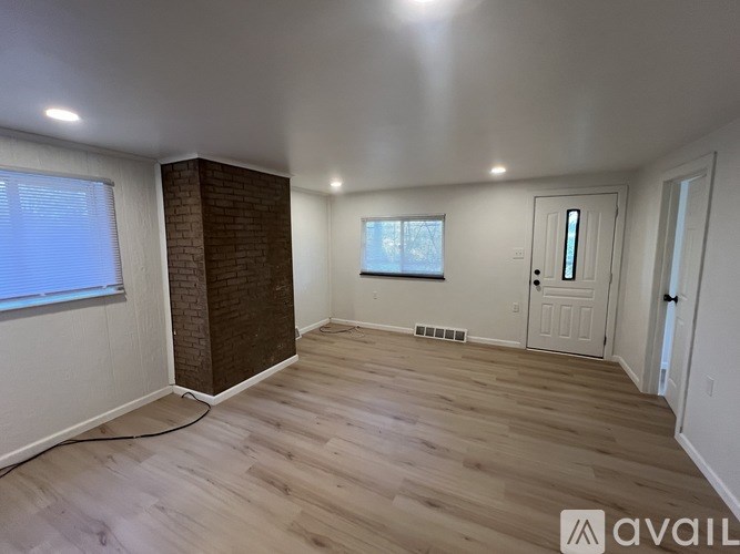 A room with wooden flooring and a brick pillar.