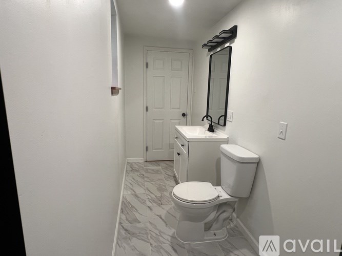 A bathroom with a toilet, sink, and mirror.