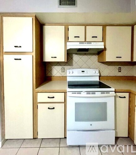 A white oven and microwave in a kitchen with wooden cabinets.