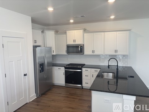 A kitchen with white cabinets and a black countertop.