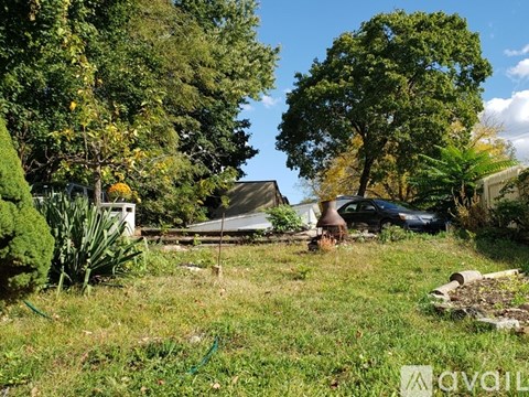 A car is parked in a yard with trees and grass.