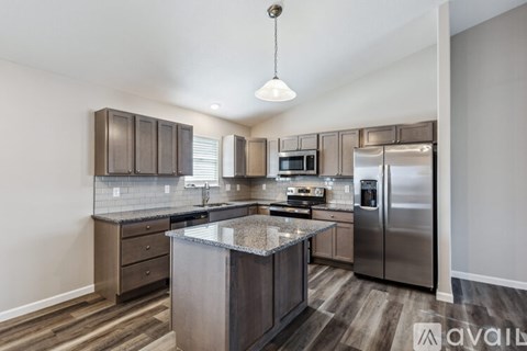 A modern kitchen with stainless steel appliances and wooden flooring.