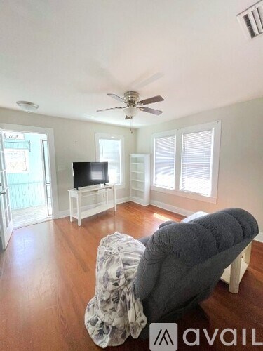 A living room with a grey couch and a television on a stand.