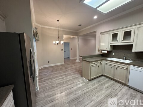 A kitchen with a refrigerator on the left and a sink with a countertop.