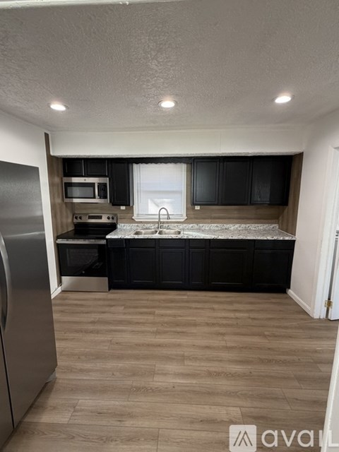 A kitchen with black cabinets and a stainless steel refrigerator.