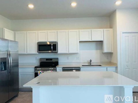 A kitchen with white cabinets and a stainless steel refrigerator.
