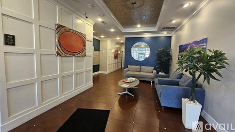 A living room with a blue couch and a round orange pillow.