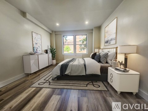 A bedroom with a large bed, a nightstand, and a rug on the floor.