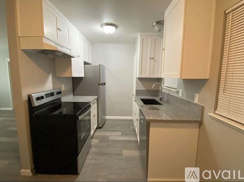 A kitchen with black appliances and beige cabinets.