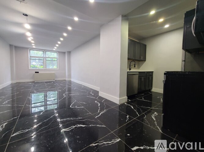 A spacious room with wooden floors and a large window.