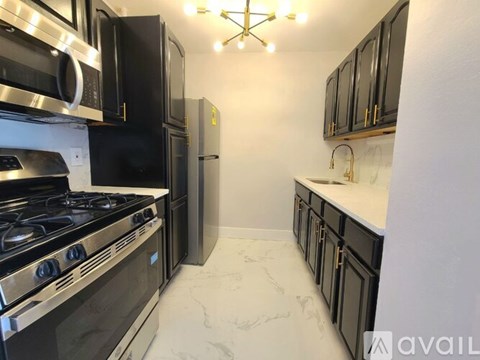 A kitchen with black cabinets and a stainless steel stove top oven.