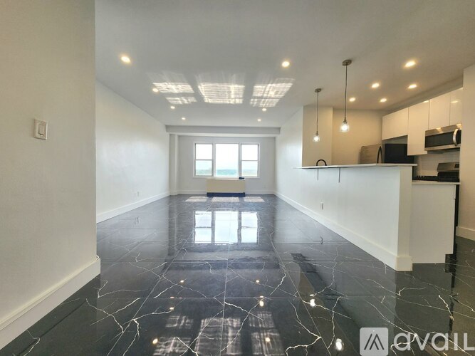A spacious room with marble flooring and a kitchen area in the background.