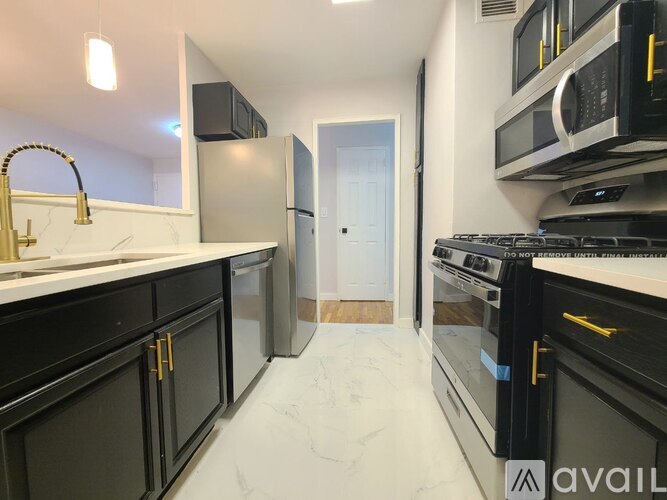 A kitchen with black marble flooring and white cabinetry.
