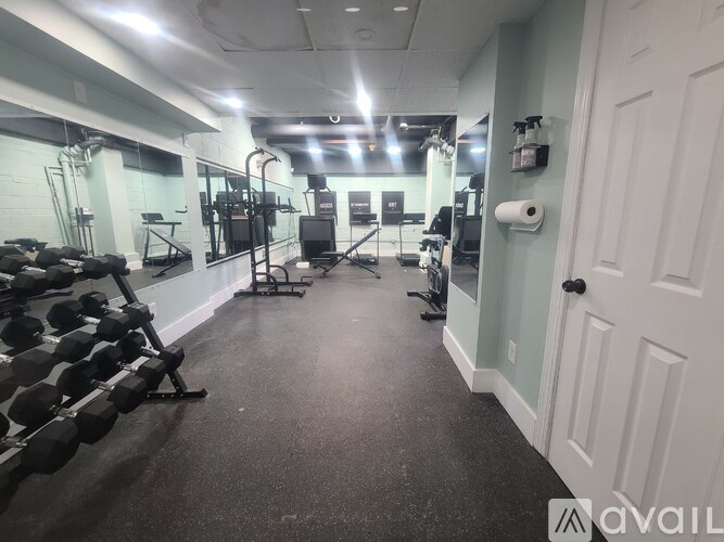 A gym with a row of dumbbells on the left and a mirror on the wall.