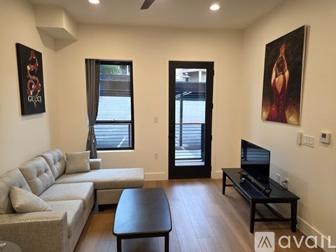 A living room with a grey couch, a black coffee table, and a painting on the wall.